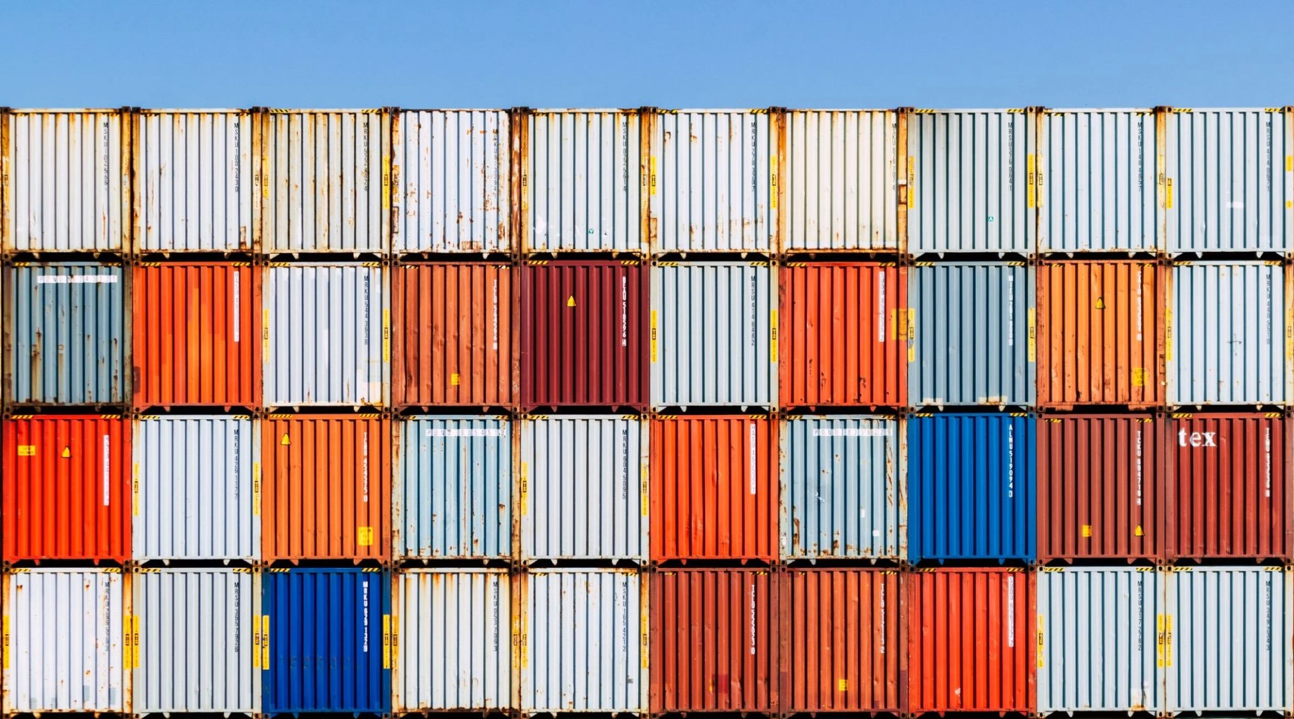 Contenedores de carga apilados que representan la preparación de una empresa para exportar y los requisitos necesarios para iniciar exportaciones