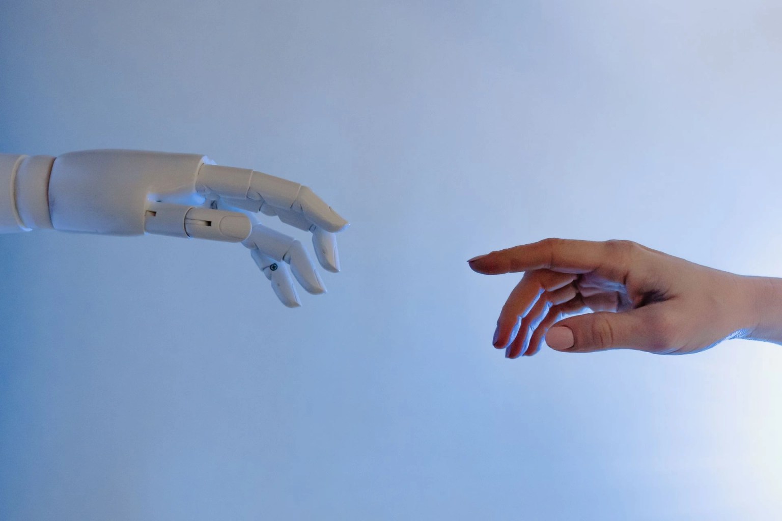 Mano humana y mano robot acercandose, imagen para ilustrar la medicion de la tasa de alucinaciones en inteligencia artificial.
