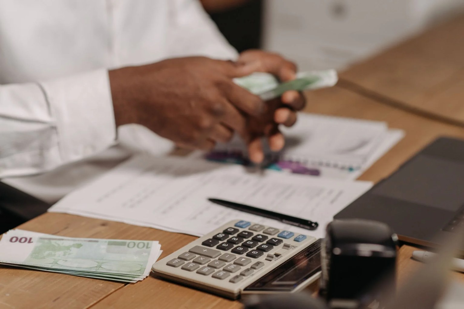 Persona revisando dinero, calculadora y documentos financieros, imagen ilustrativa sobre el Beneish M-Score y la detección de posibles manipulaciones contables